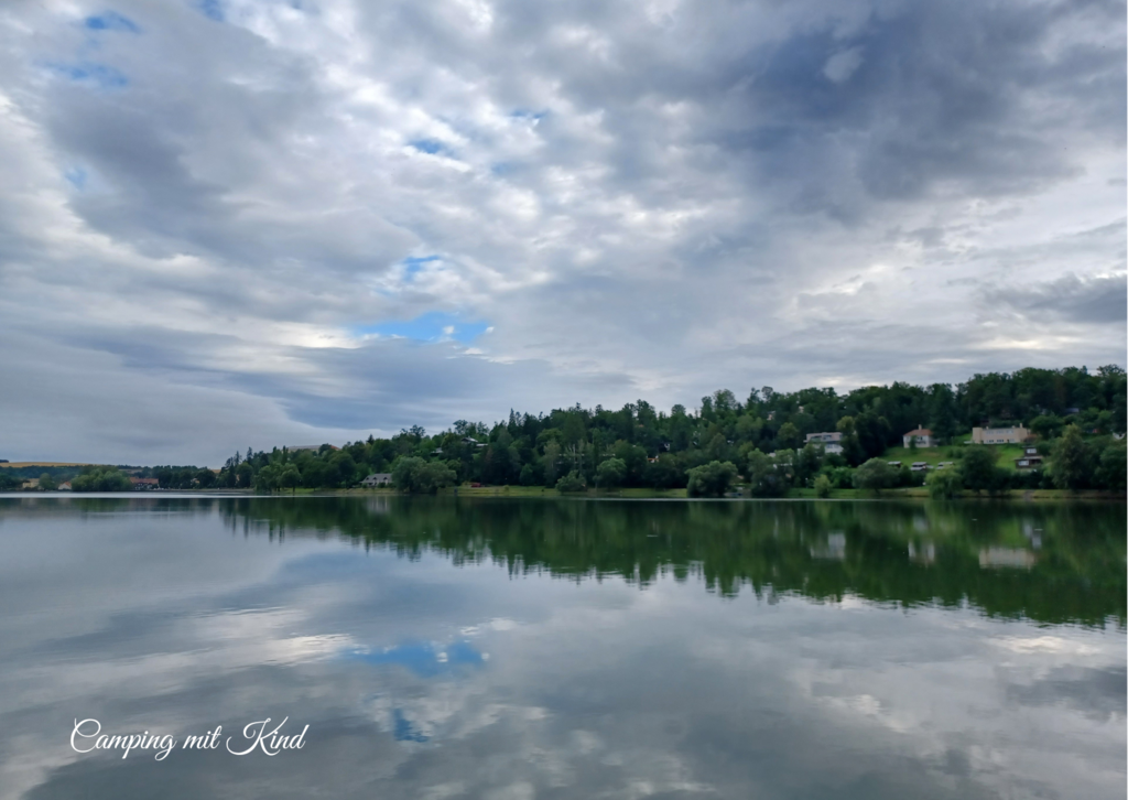 Ein See, dahinter befindet sich ein Wald.